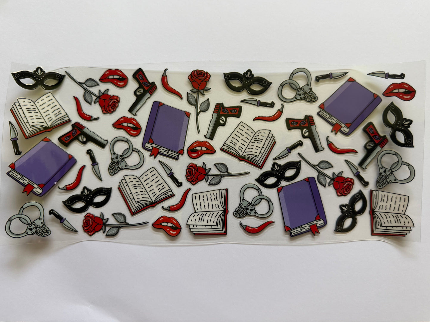 Collection of decorative pins with books, masks, and other items on a white background