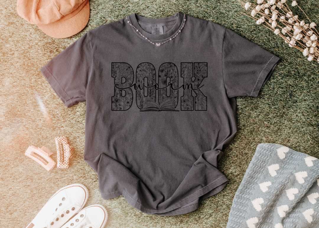Gray t-shirt with text on a textured surface with accessories around