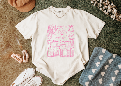 White t-shirt with pink graphic design on a textured surface with accessories.