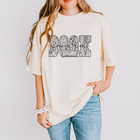 Person wearing a cream-colored t-shirt with 'Book' design on a plain background