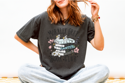 Person wearing a dark gray t-shirt with a graphic design and text, sitting on a white surface.